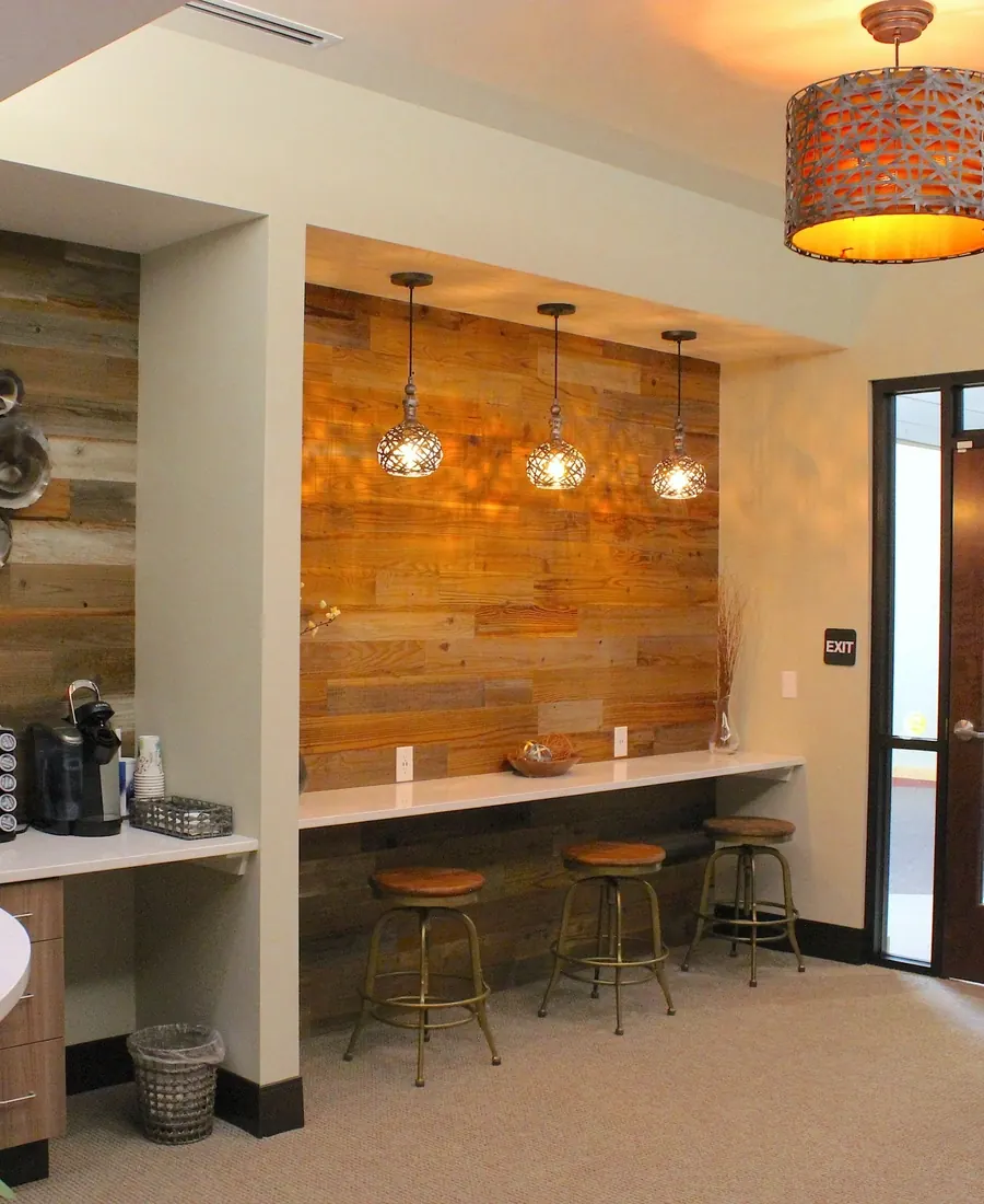 The coffee bar in the reception area, with a reclaimed wood wall and pendant lights.