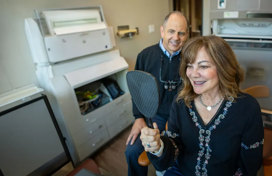 Dr. Slaman and a patient looking at her new smile in a hand mirror.